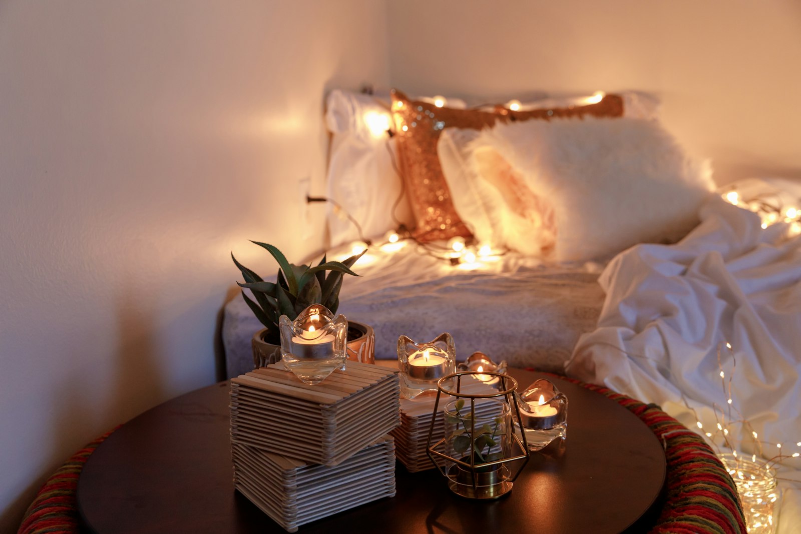 A glass candle holder glowing on a wooden table at night